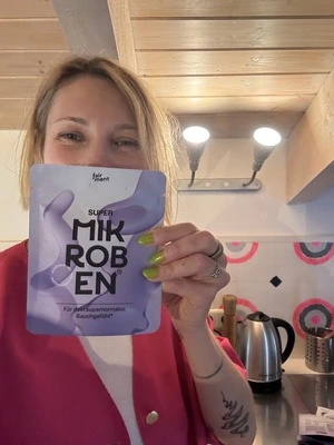 Person holding a packet labeled 'Super Mikroben' in a kitchen setting.