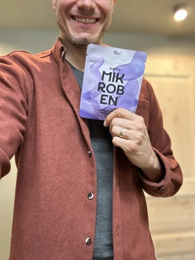 Person holding a packet labeled 'Super Mikroben' with a smile.