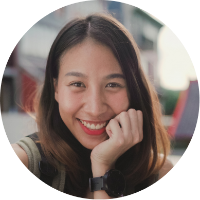 Smiling person with long hair, resting chin on hand, wearing a watch.