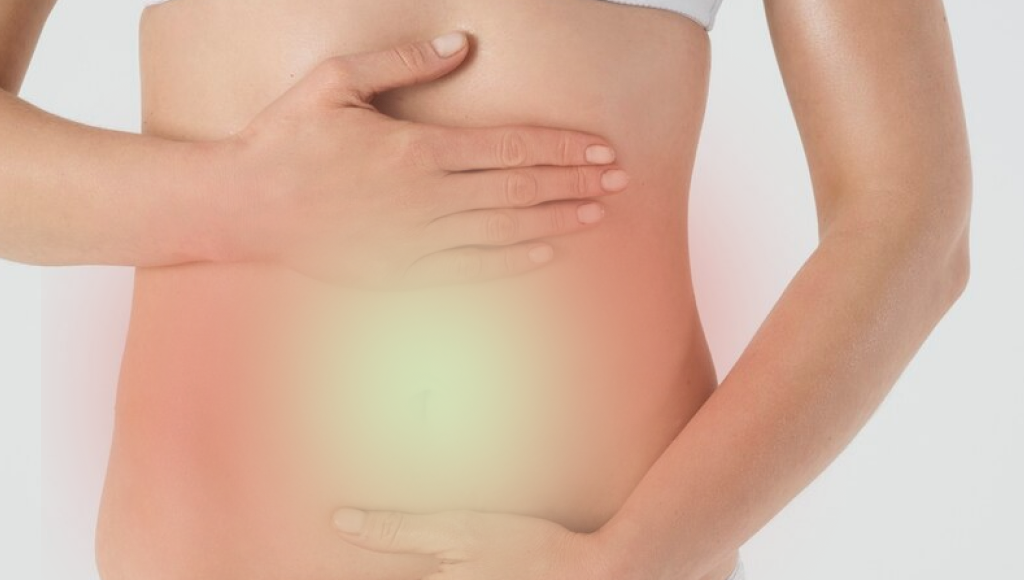 Person holding their stomach with a glowing effect on the abdomen.
