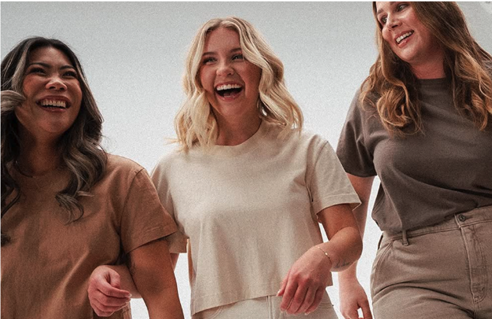 Three women smiling and walking together in casual clothing.