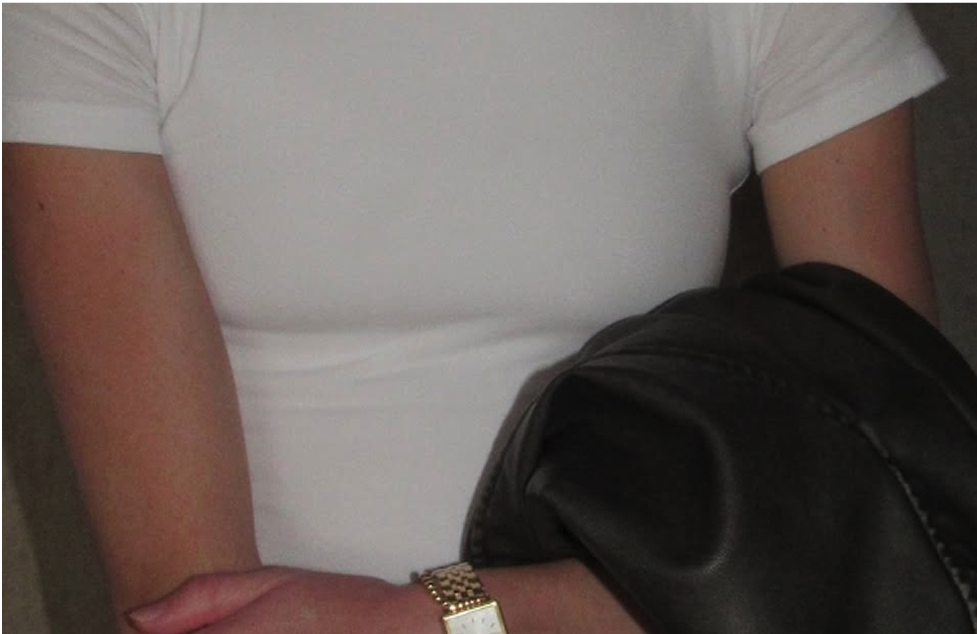 Person in white shirt holding a black jacket, wearing a gold watch.