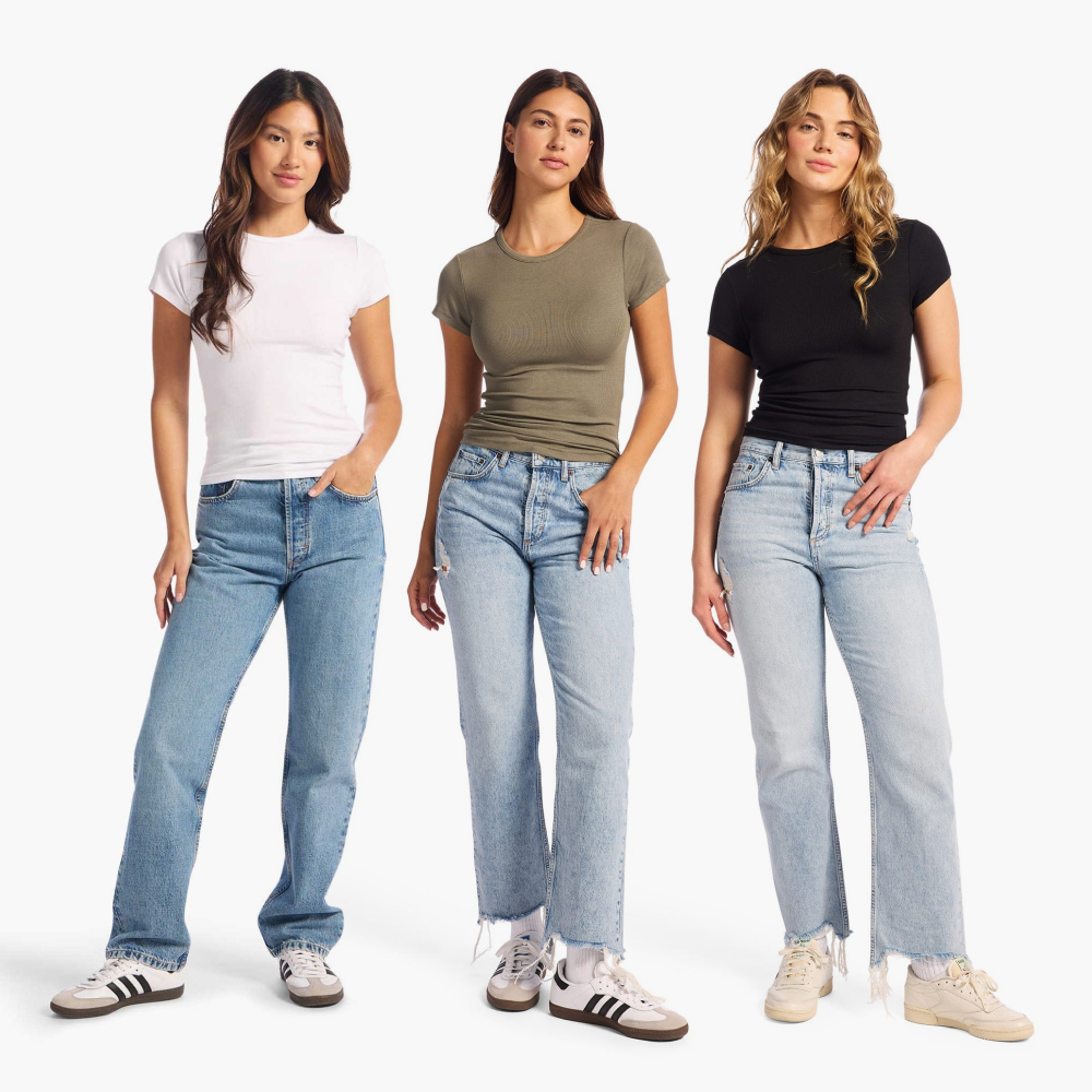 Three women wearing jeans and t-shirts, standing against a white background.
