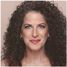 Person with curly hair smiling against a neutral background.