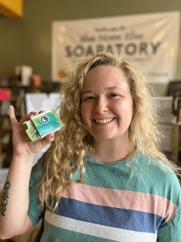 Person holding a bar of soap, smiling in a store.