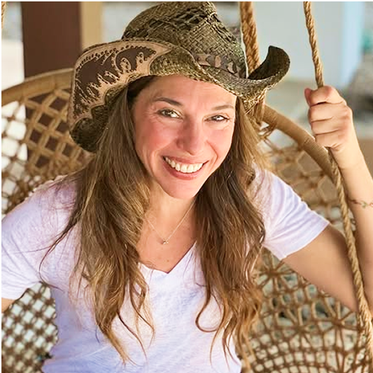 Smiling person wearing a cowboy hat, sitting on a woven swing.