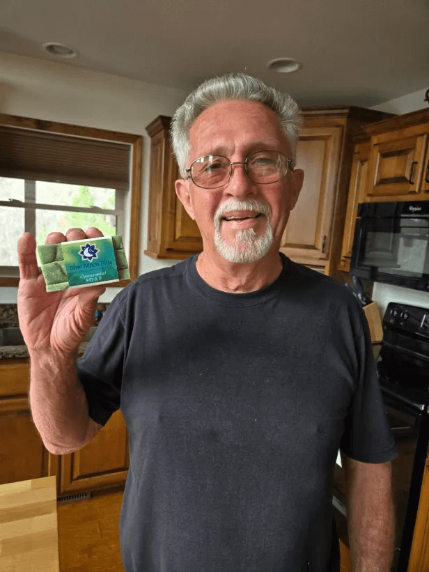 Man holding a bar of soap in a kitchen.