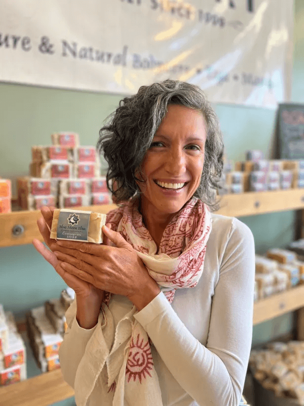 Smiling person holding a bar of soap in a store.