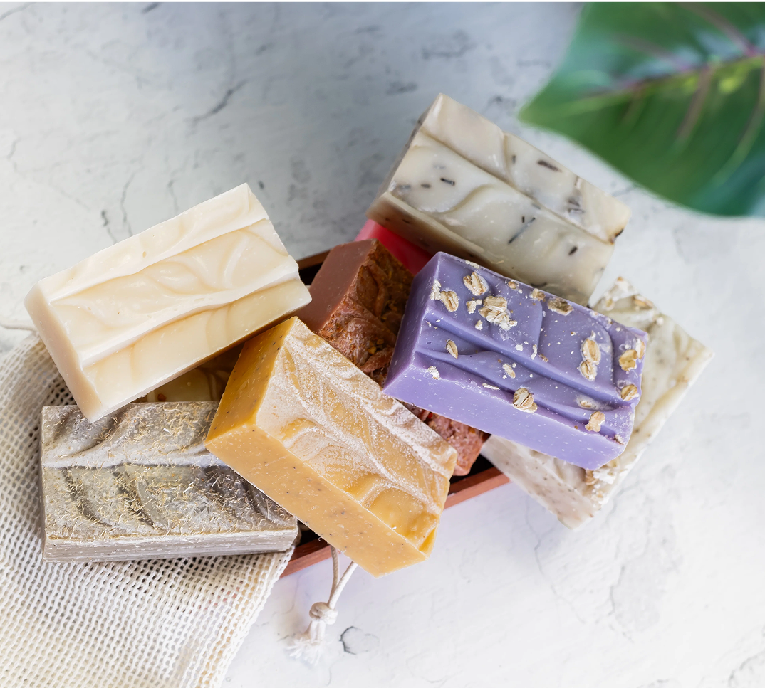 Assorted handmade soap bars stacked on a light surface.