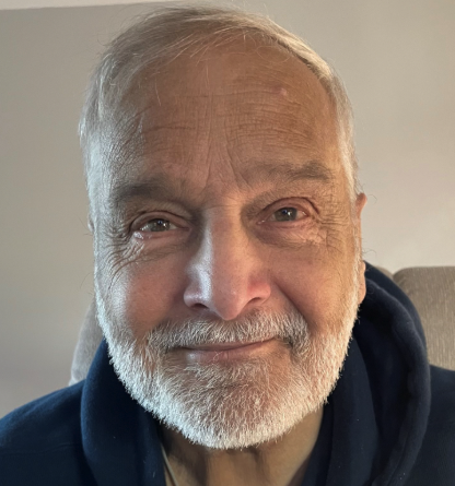 Elderly man with a beard smiling at the camera.