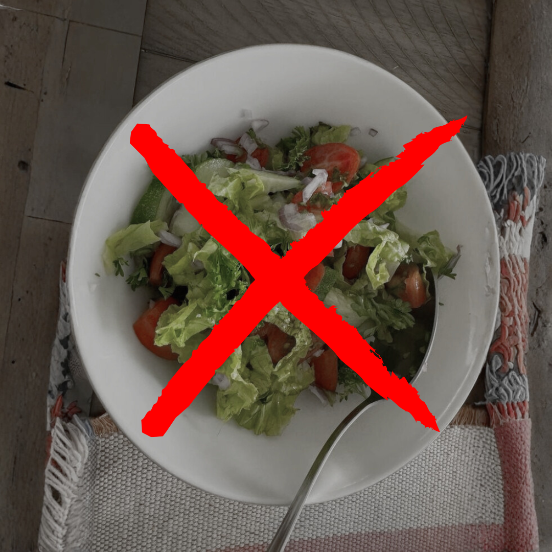A salad in a bowl with a red 'X' over it, spoon beside the bowl.