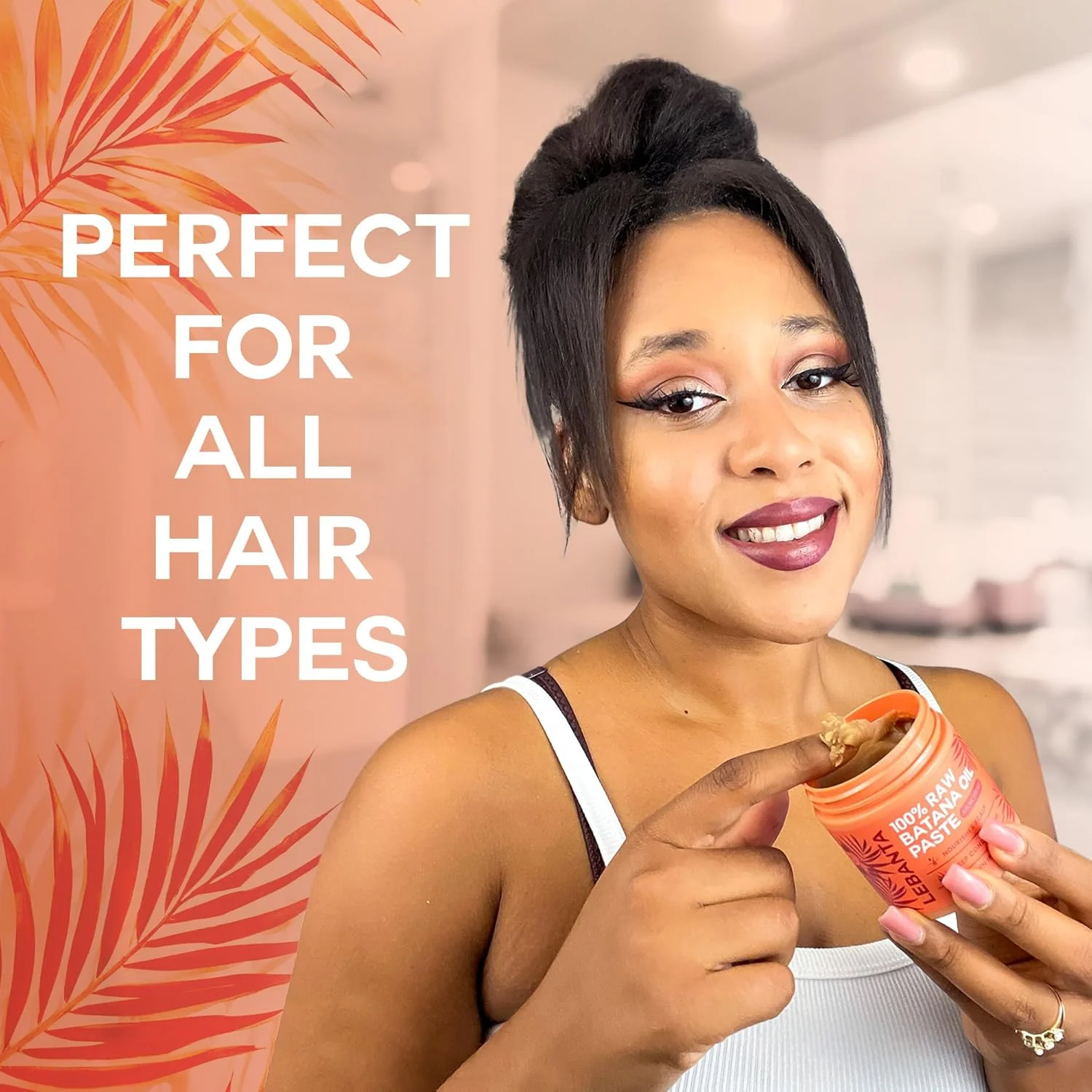 A smiling woman holds an open jar of hair paste, dipping her finger into the product.