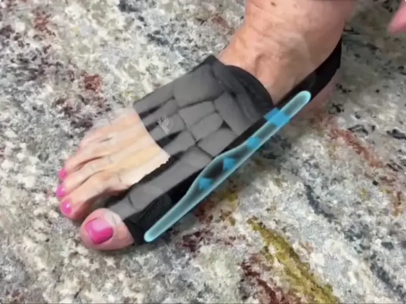 Foot wearing a black orthopedic brace with pink toenail polish.