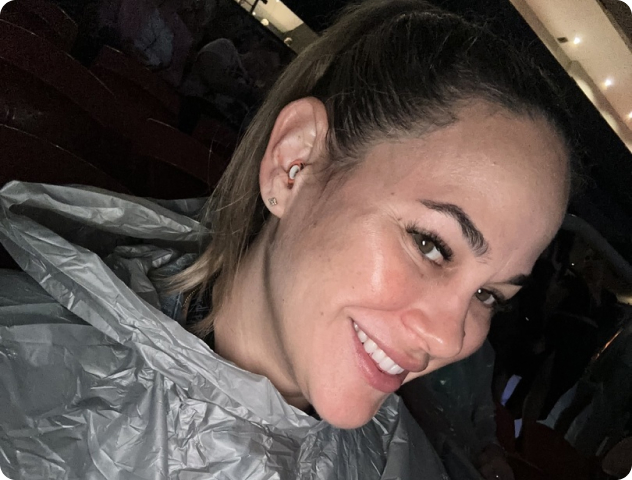 Woman smiling indoors, wearing a gray rain poncho.