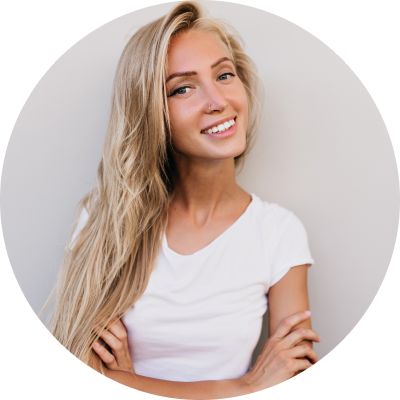 Person with long blonde hair smiling, wearing a white t-shirt, arms crossed.