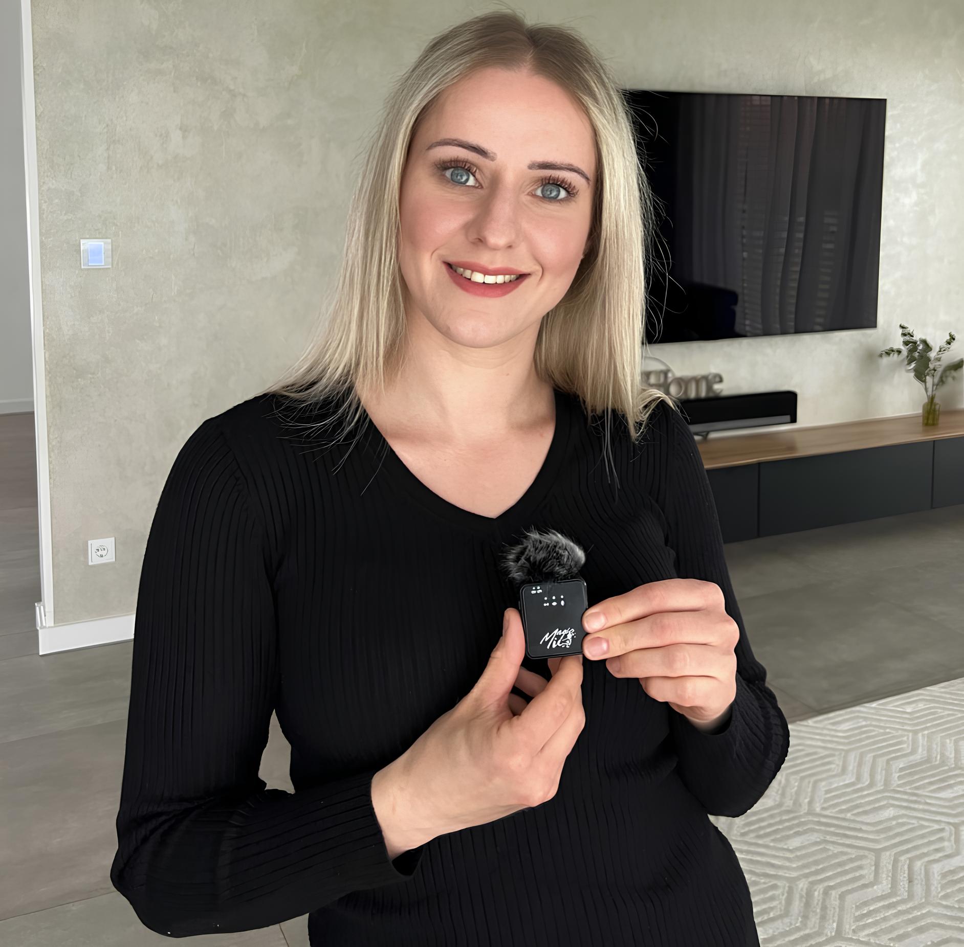 Person holding a small microphone in a modern living room.