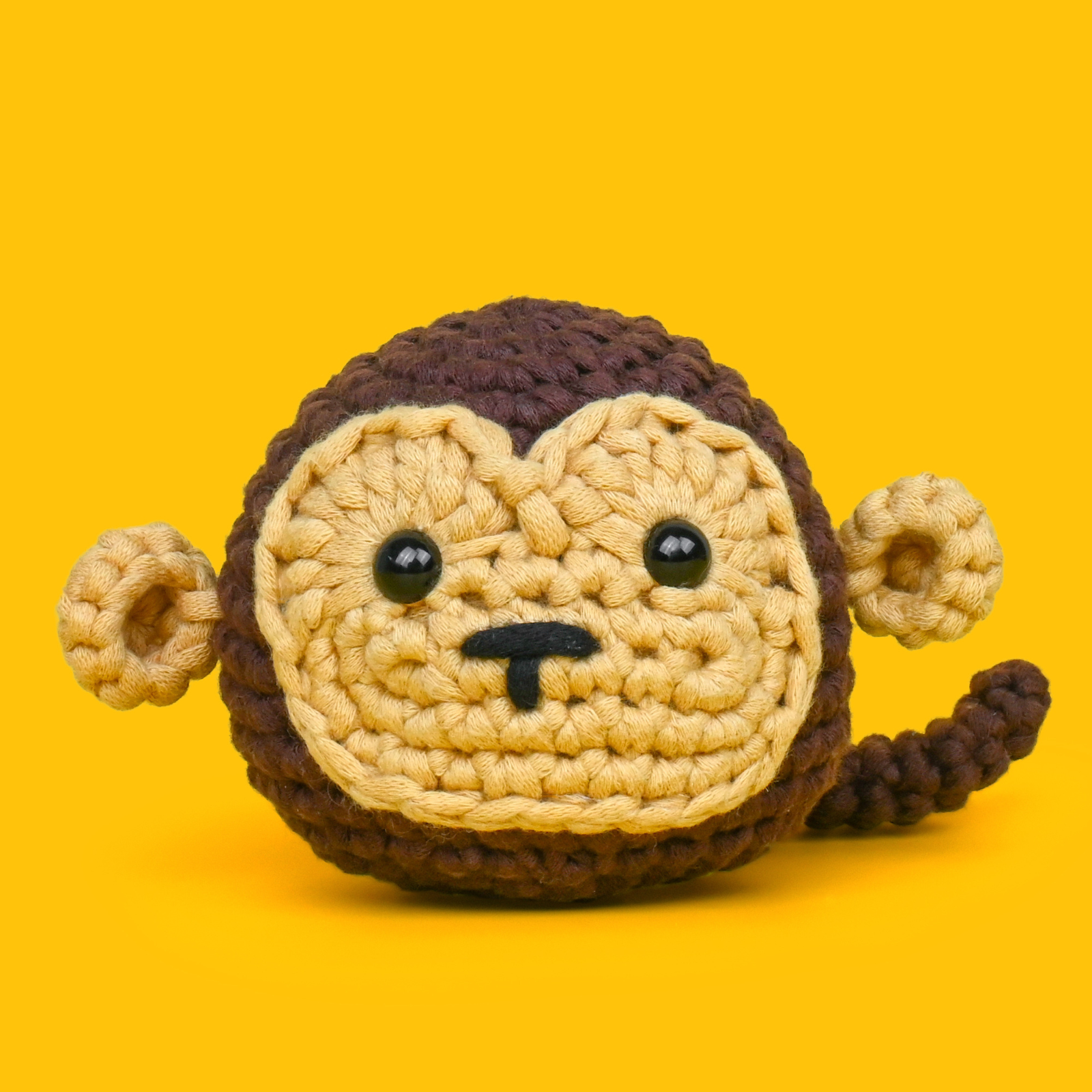 Crocheted monkey toy on a yellow background.