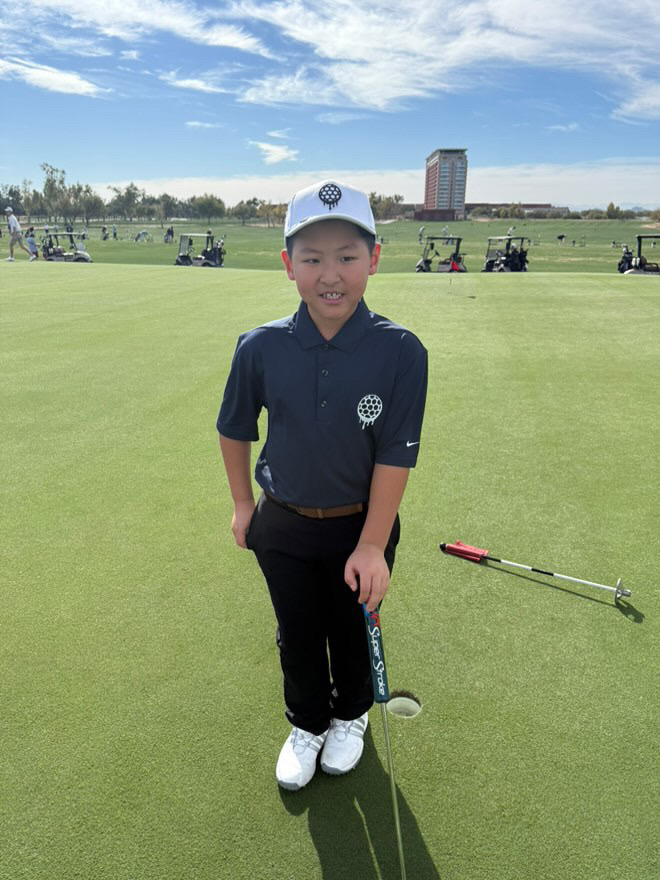 Young golfer standing on a green with a putter.