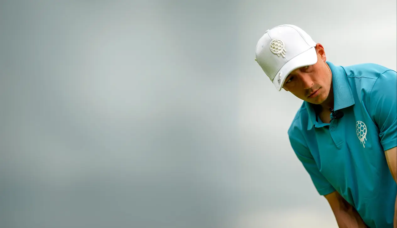 Person in a blue shirt and white cap looking down, with a blurred background.