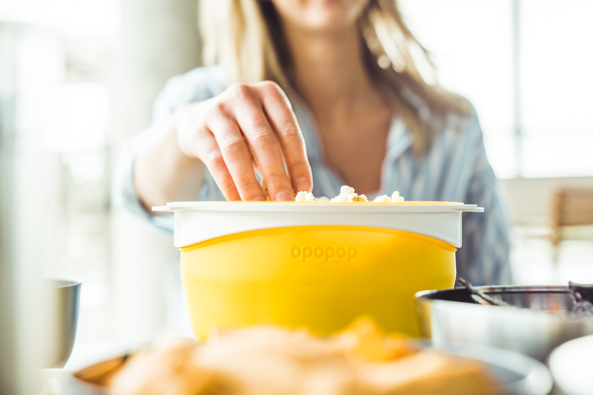 Person reaching into a yellow popcorn bowl.