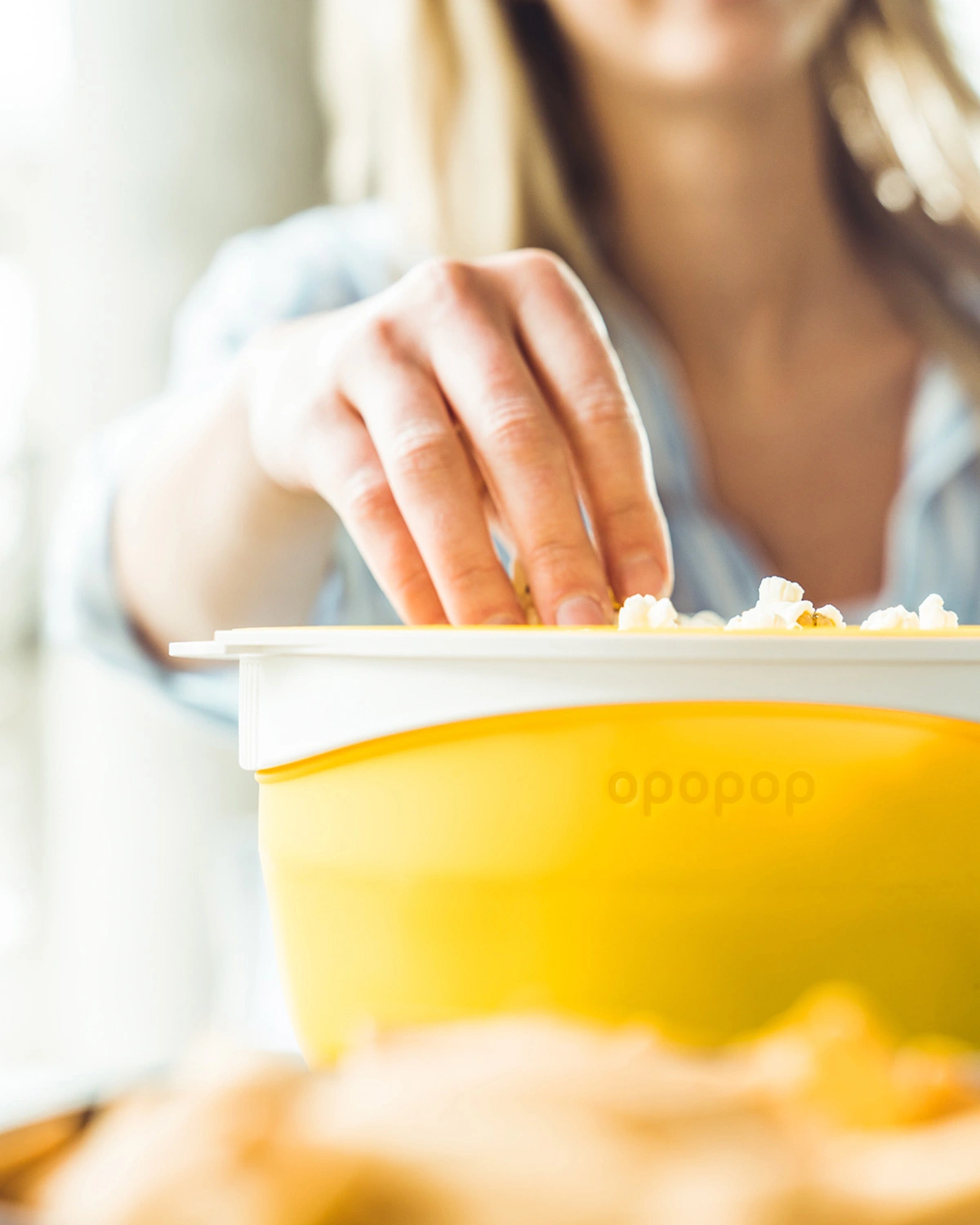 Person reaching into a yellow popcorn container.