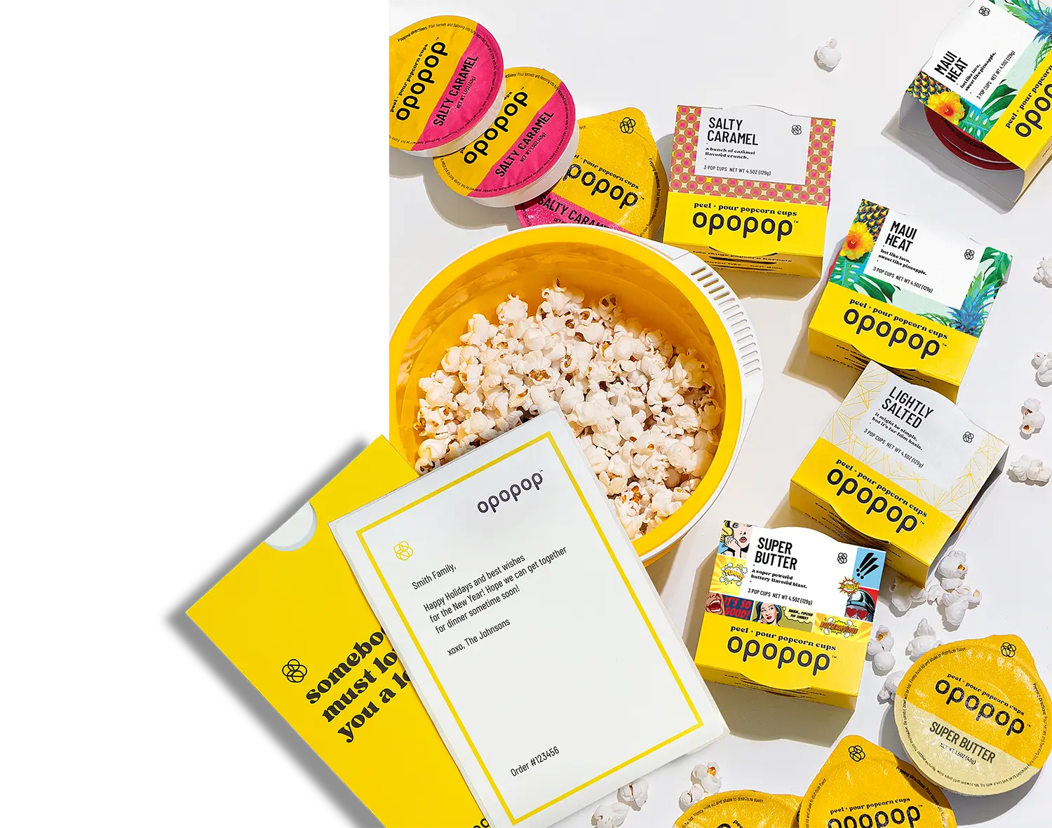 Popcorn in a yellow bowl surrounded by various flavored popcorn packages and a note.