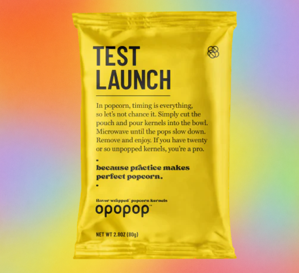 Yellow popcorn bag labeled 'Test Launch' on a rainbow gradient background.