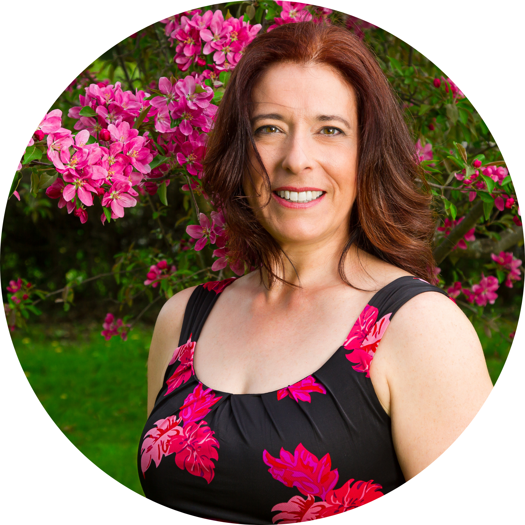 Woman smiling in front of pink flowering tree.