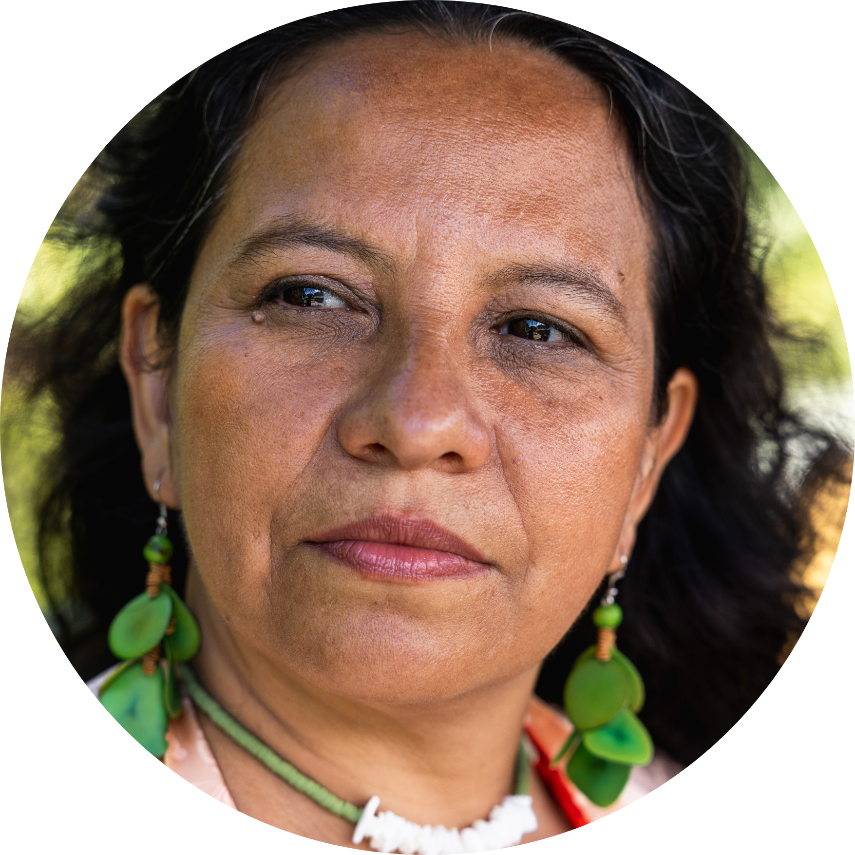 Portrait of a woman with green earrings and necklace, looking to the side.
