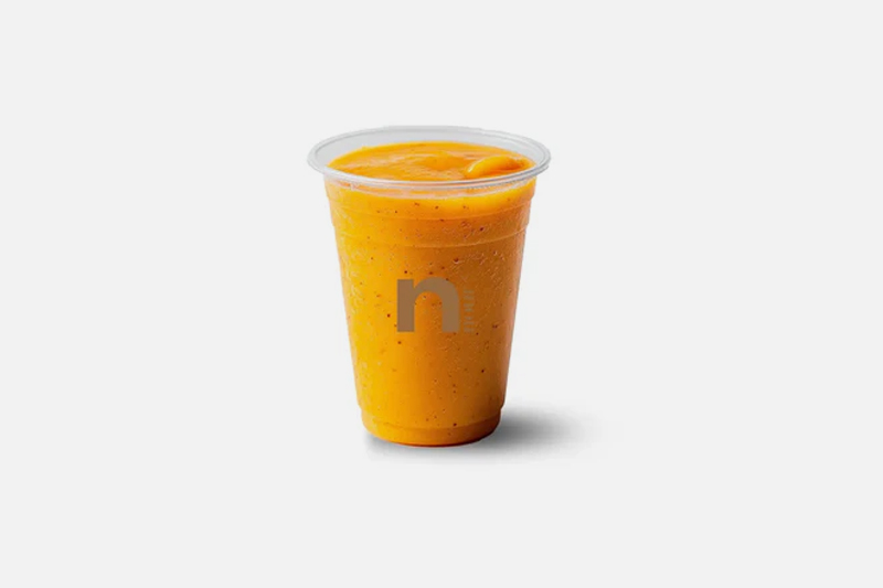 A plastic cup filled with orange smoothie on a white background.
