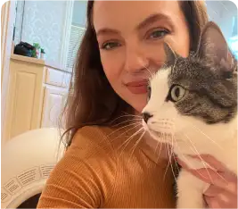 Woman smiling with a black and white cat indoors.