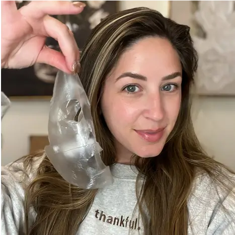 Person holding a transparent face mask, smiling.