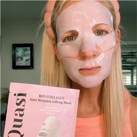 Person wearing a facial mask, holding a pink anti-wrinkle lifting mask package.