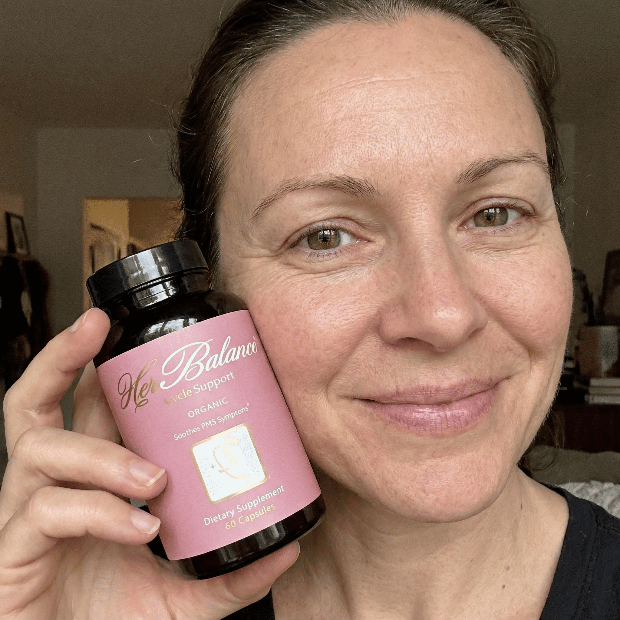 Person holding a bottle of dietary supplement labeled 'Her Balance'.