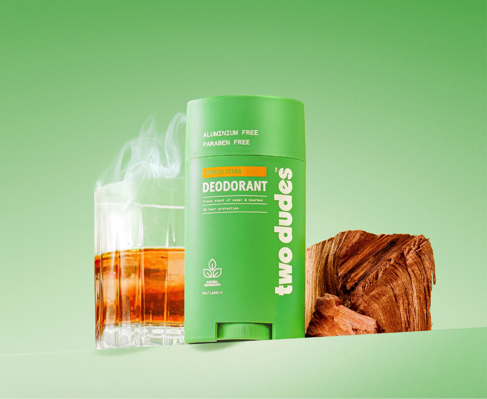 A stick of Two Dudes deodorant next to a glass of bourbon and a block of cedar wood.
