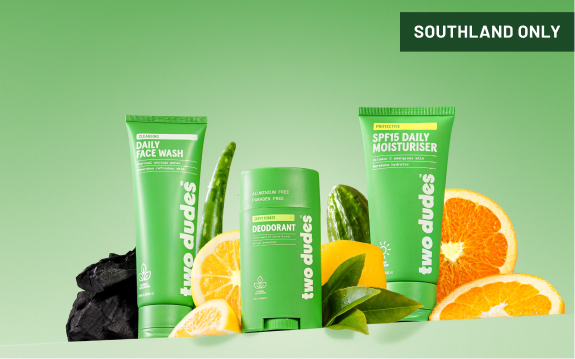 Two Dudes skincare products—face wash, deodorant, and moisturiser—are displayed with charcoal, citrus fruits, and aloe.
