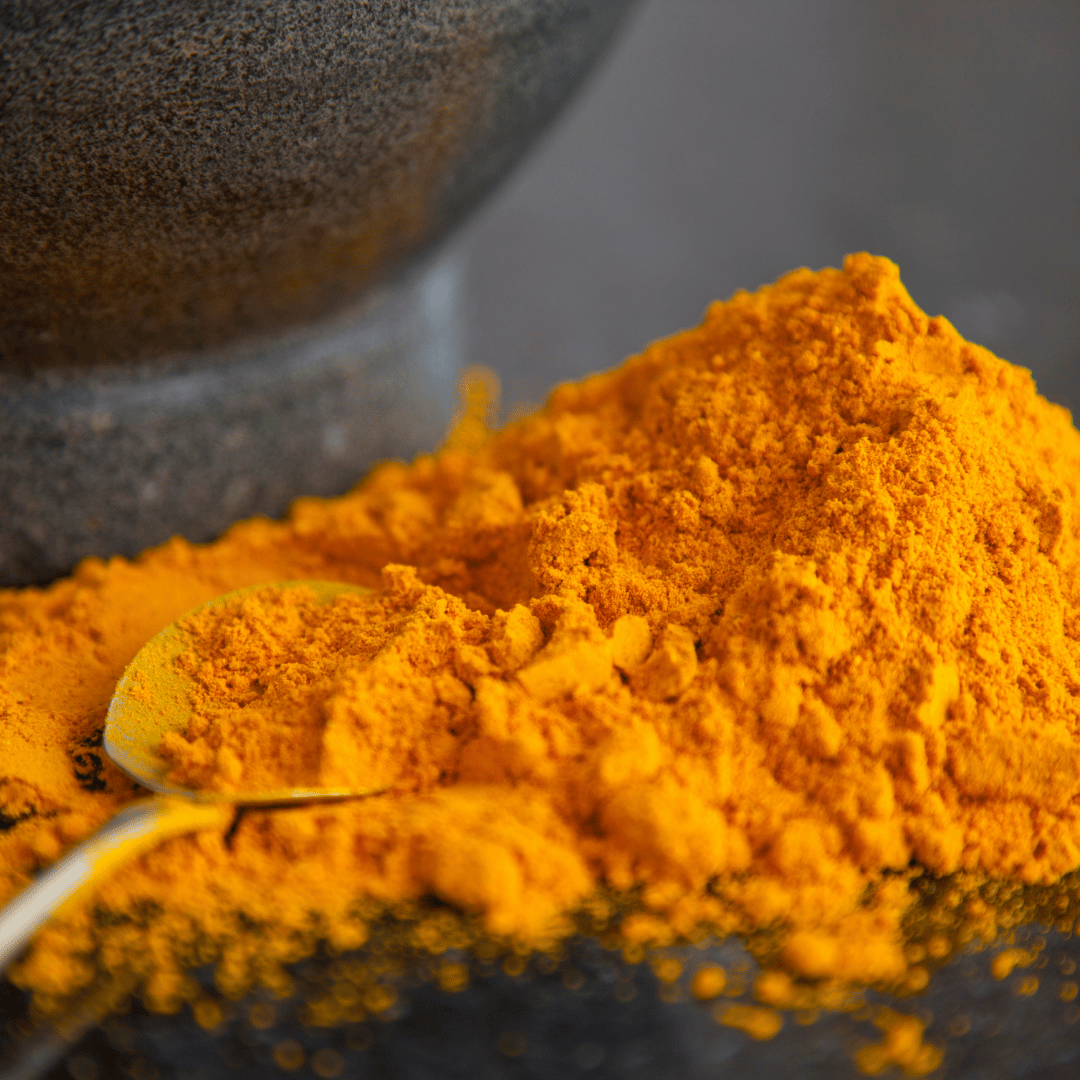 A pile of bright orange powder with a spoon on a dark surface.