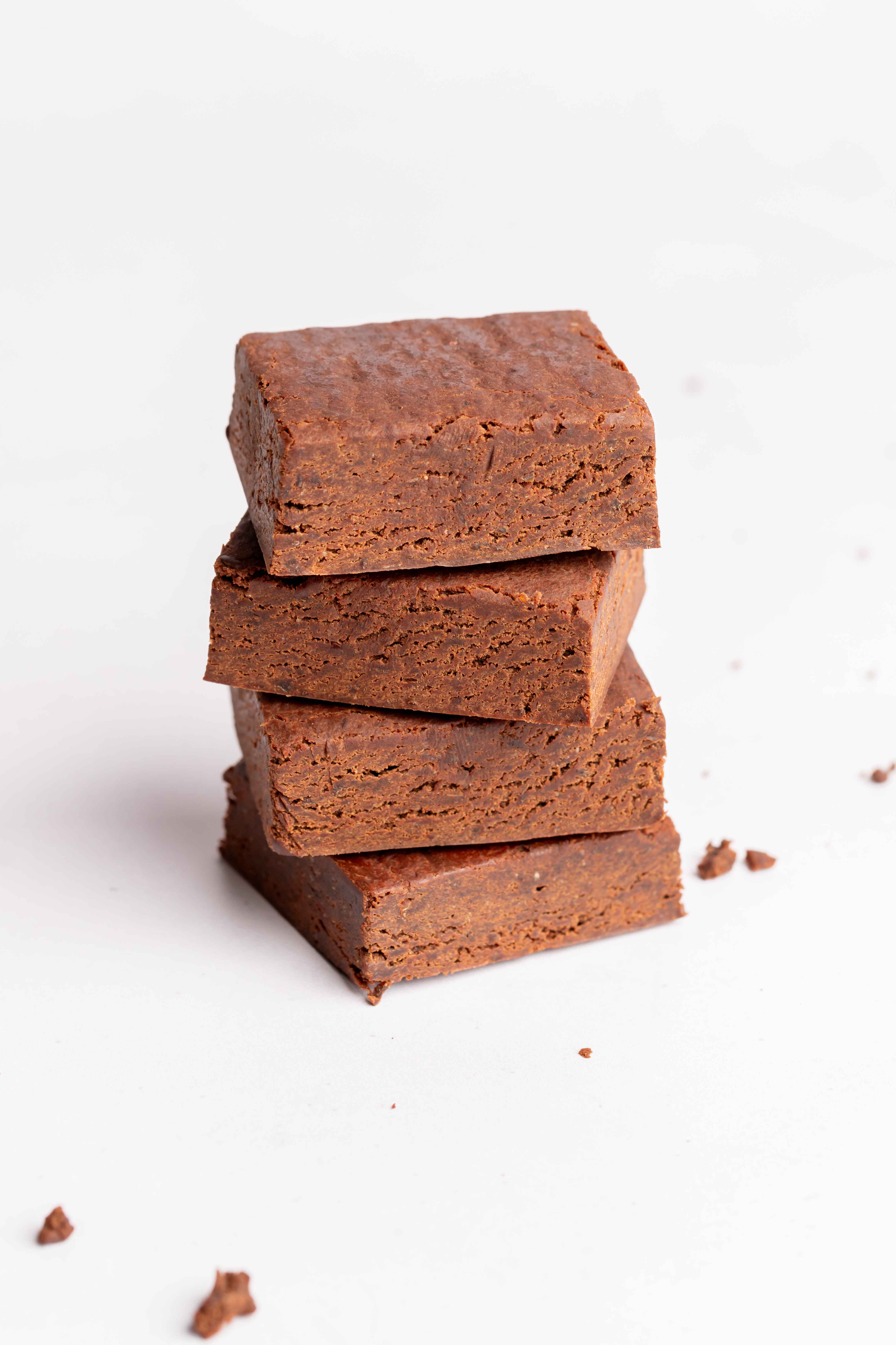 Stack of four chocolate brownies on a white background.