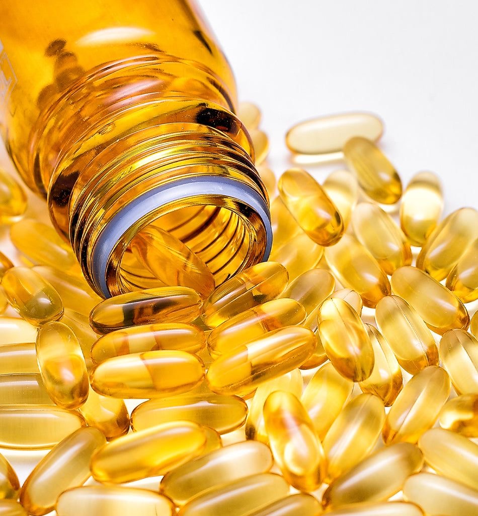 A bottle of yellow capsules spills onto a white surface.