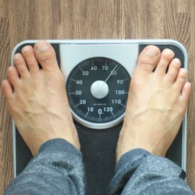 Feet on a mechanical bathroom scale showing weight.