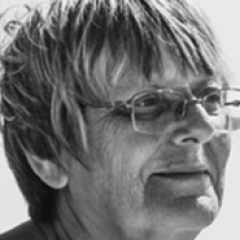 Black and white photo of a person wearing glasses, looking to the side.