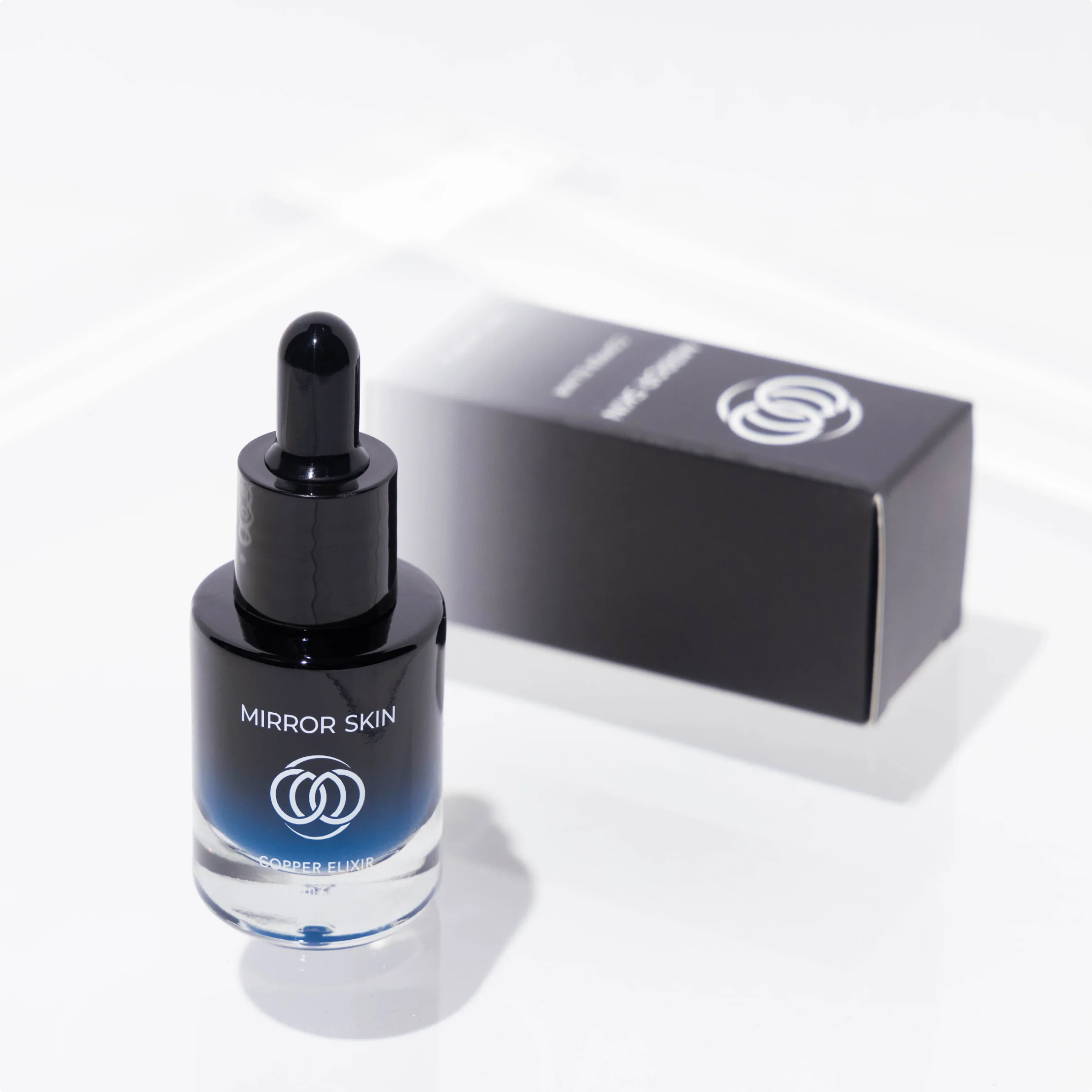 Black dropper bottle labeled 'Mirror Skin' next to a black box on white background.