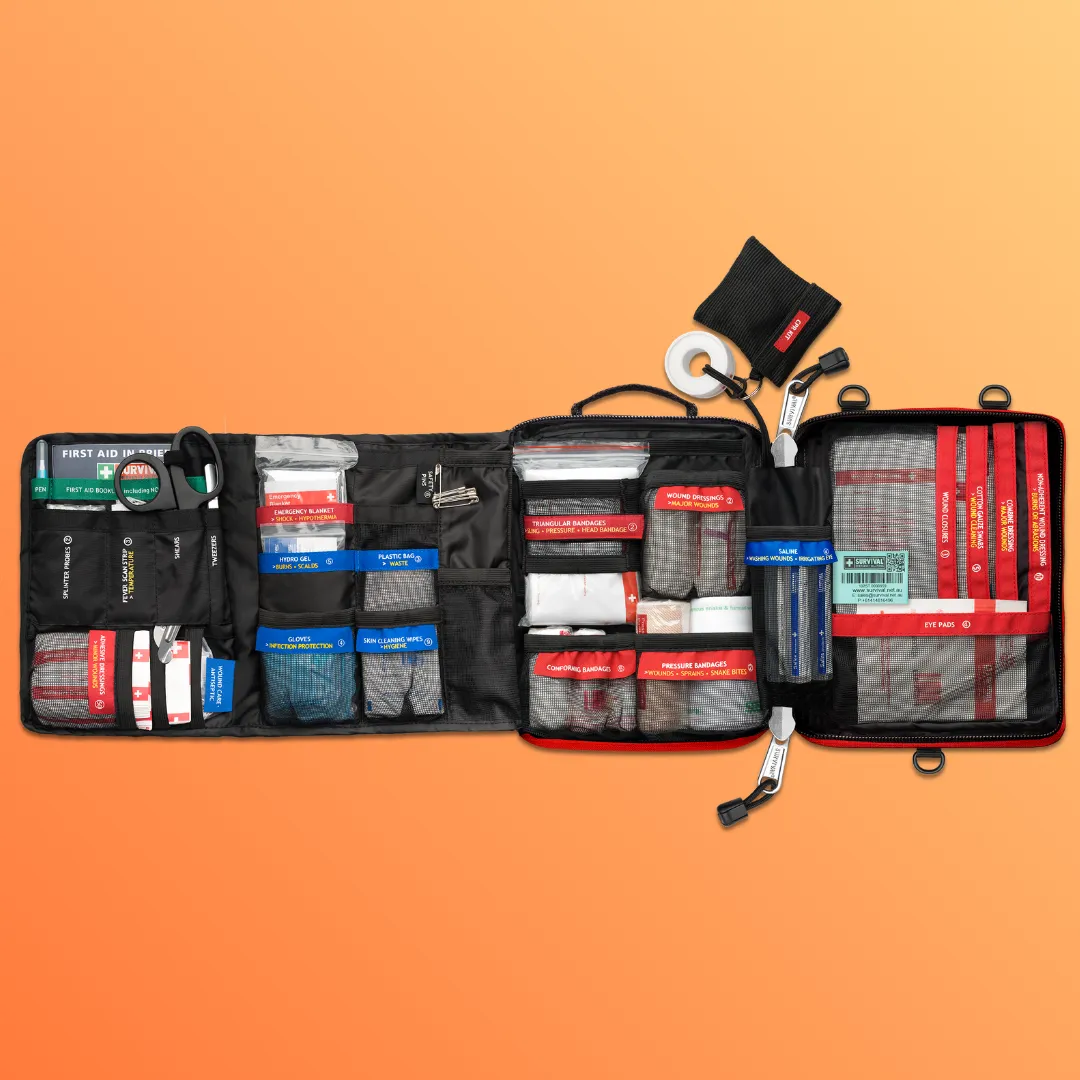 A fully stocked first aid kit is laid open on an orange background, displaying its organized contents.