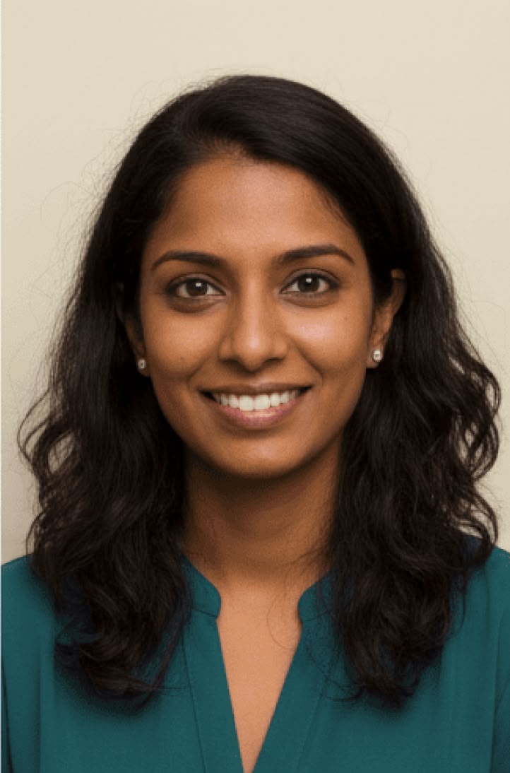 Person with wavy black hair smiling against a plain background.