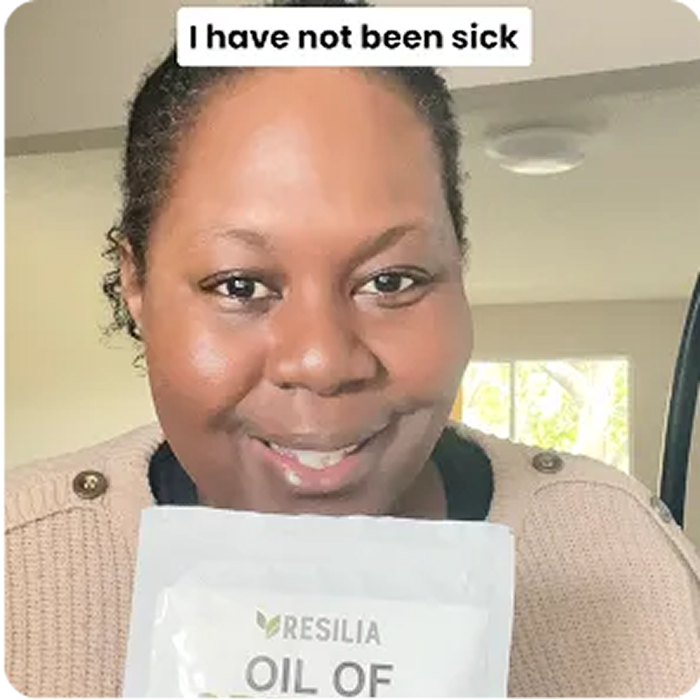 Person holding a packet labeled 'Resilia Oil of'. Text reads: 'I have not been sick'.