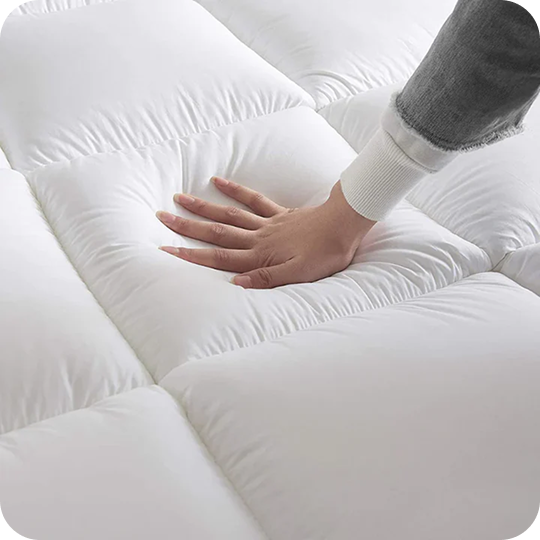 Hand pressing down on a white, quilted mattress surface.
