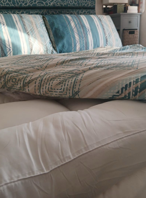 A bed with blue and white patterned bedding and pillows.