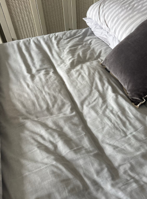 Unmade bed with white sheets and two pillows.