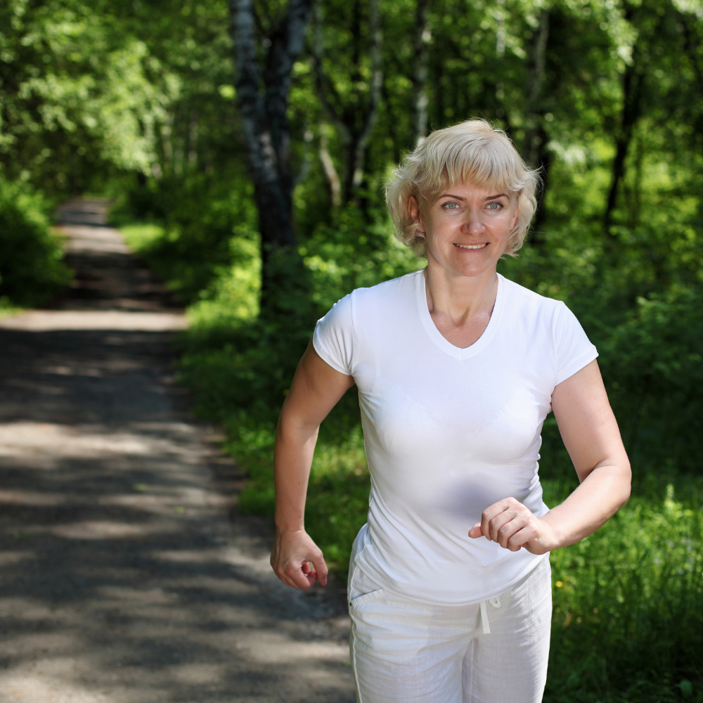 Person jogging on a forest path wearing a white shirt.