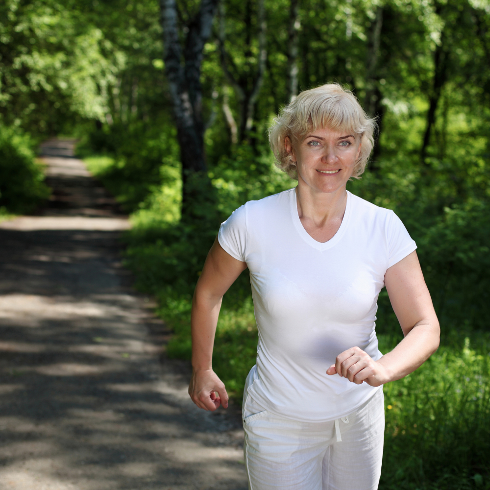 Person jogging in a wooded area wearing a white outfit.